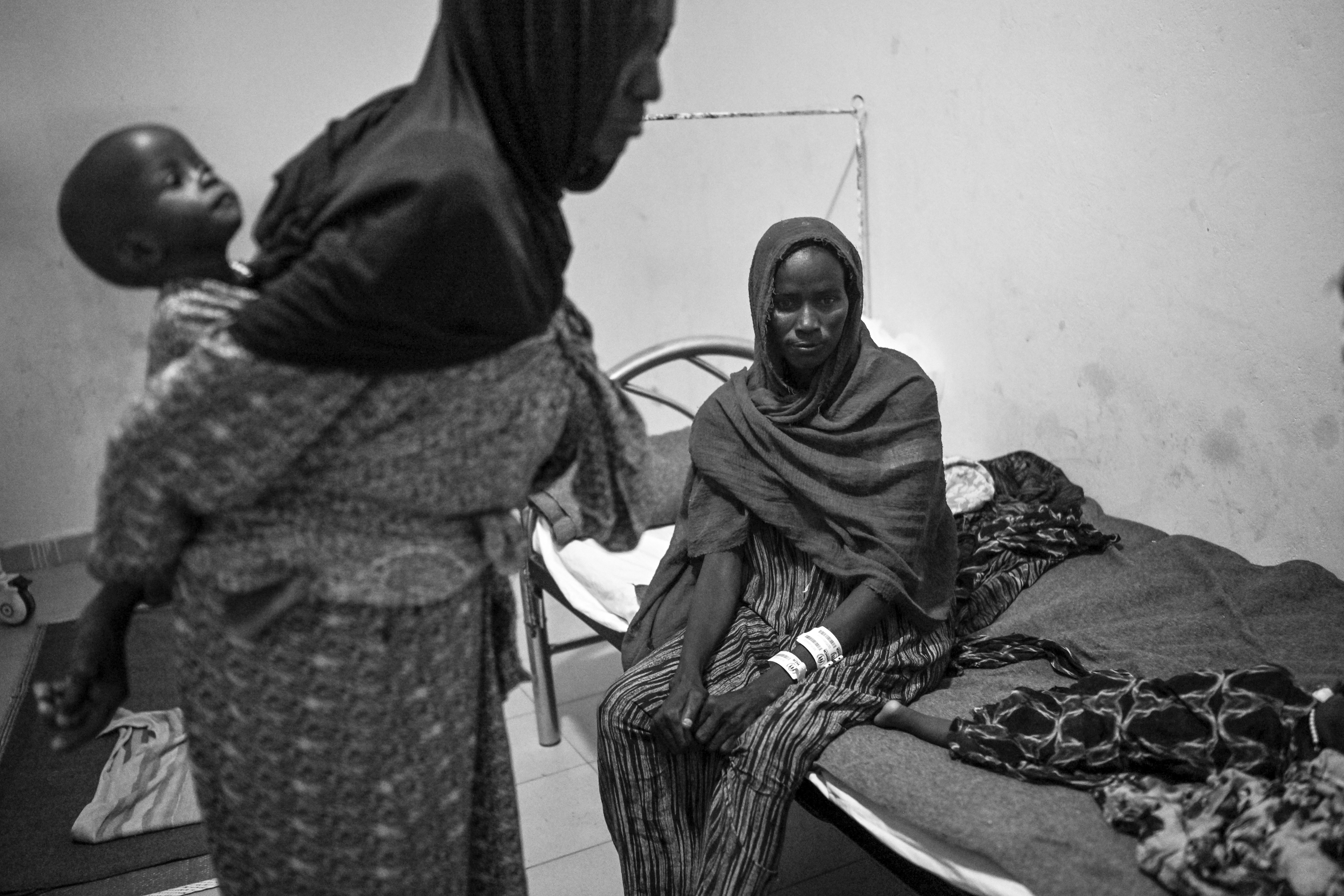 Picture of Taiba Adnan Suliman sits beside Hussein, one of her five-month-old twins, as her mother holds Hassan, the other twin, in the therapeutic-feeding center for malnourished patients at the hospital in Iriba, Chad. 