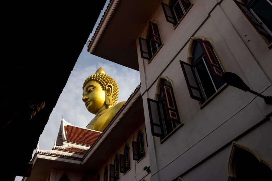 A view looking up from a courtyard toward a tall golden Buddha statue