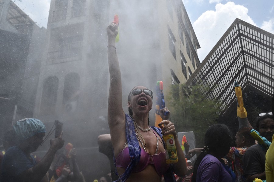 People hold up water guns in a street, surrounded by a cloud of water mist.