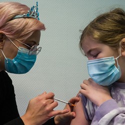 An adult gives a child her vaccine.