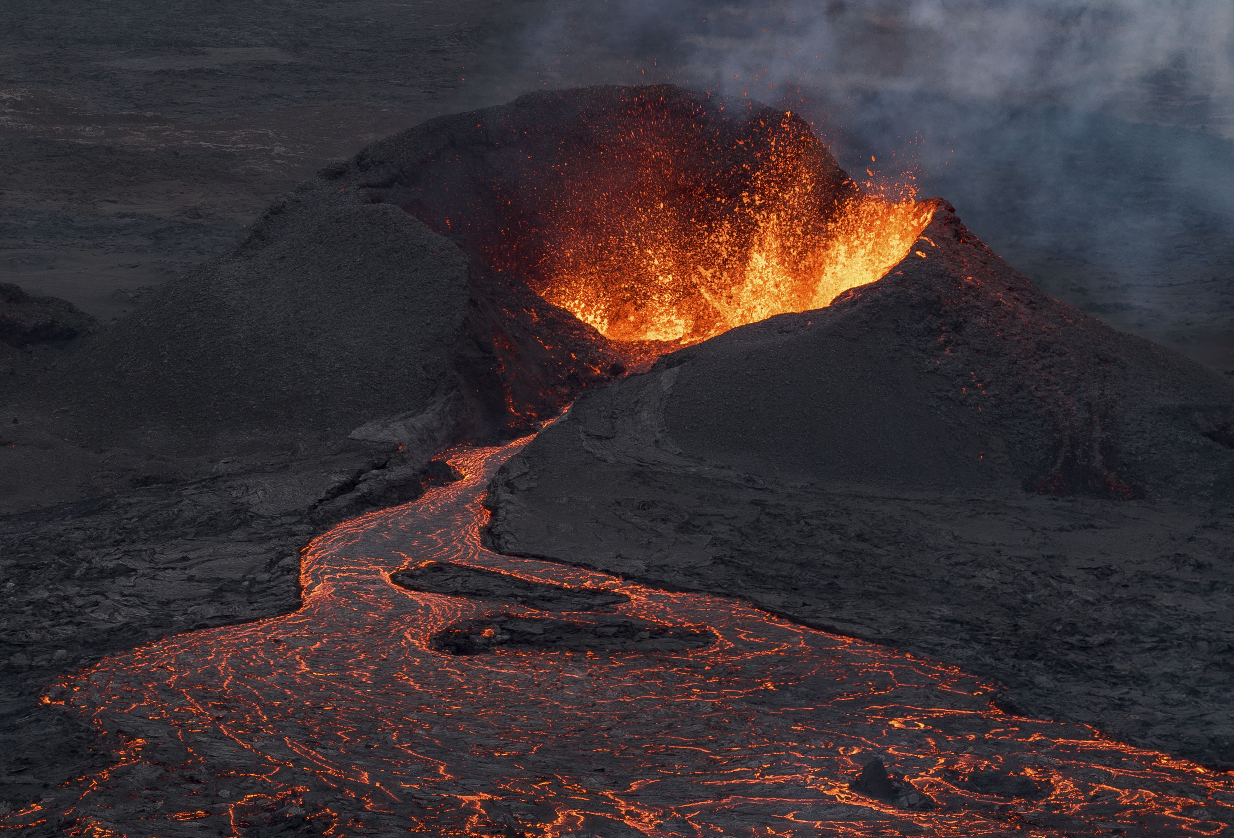 Lava erupts and flows from a volcanic crater.