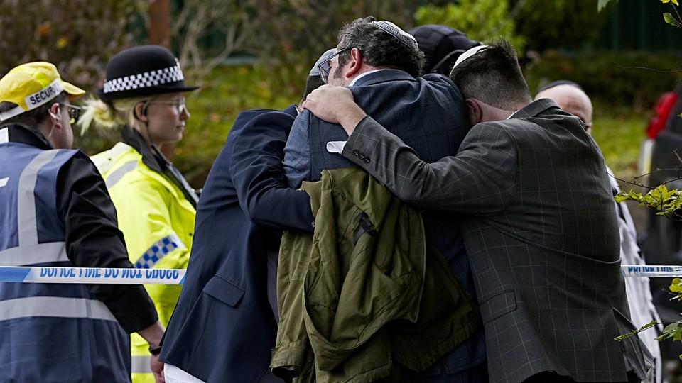 A group of people hug in front of police tape