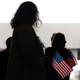 A group of people are silhouetted while holding small American flags.