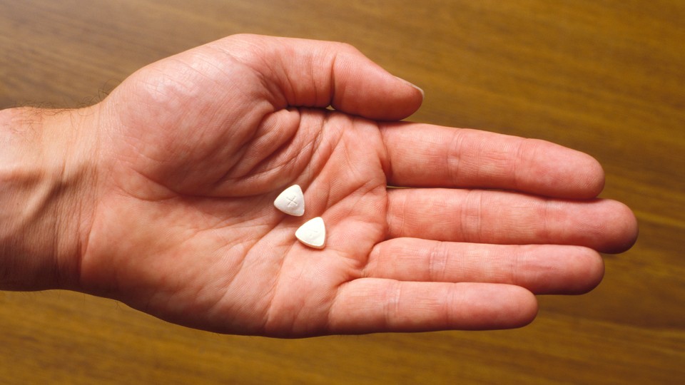 A hand holds two pills