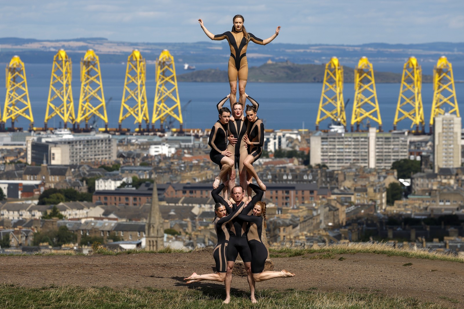 Performers pose, forming a human tower on a hill above Edinburgh.