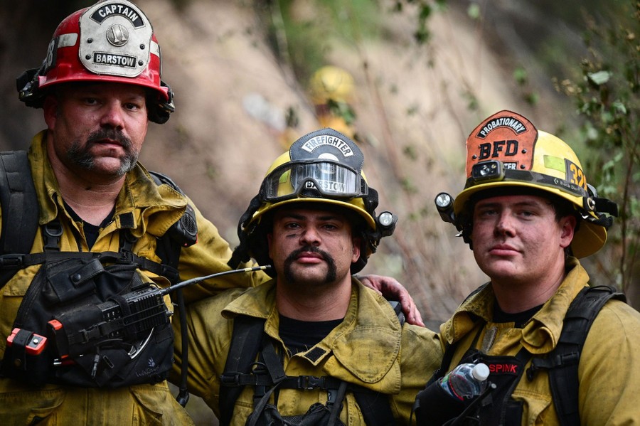 Three firefighters pose for a photo in the field.