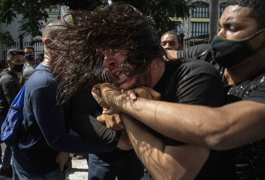 Plainclothes police detain an anti-government protester.