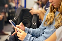 A teenager uses an iPhone while riding on public transit.