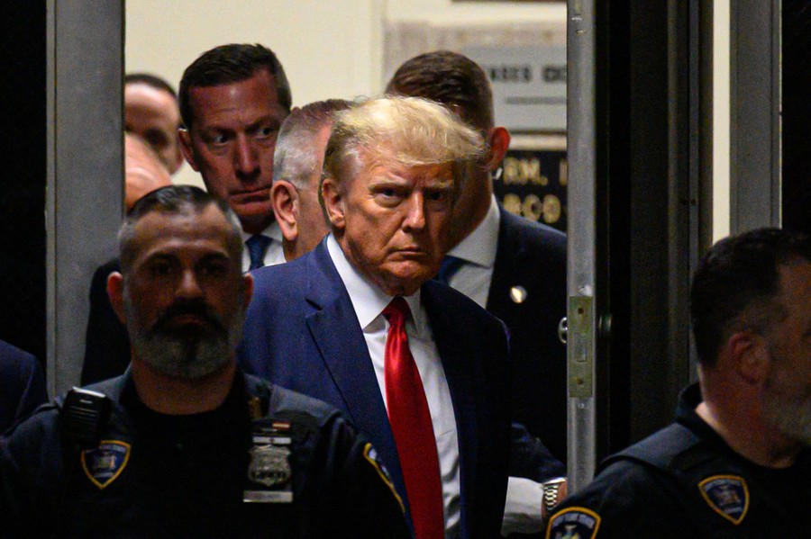 Former President Donald Trump walks through a door in a courthouse.