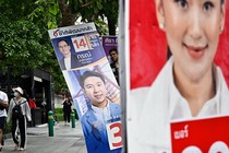 People walk past a campaign poster for opposition candidate Paetongtarn Shinawatra on a street in in Bangkok.