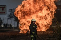 A single firefighter standing in front of a large fire.