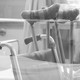 Black-and-white photo of crutches and a wheelchair in what seems to be a hospital