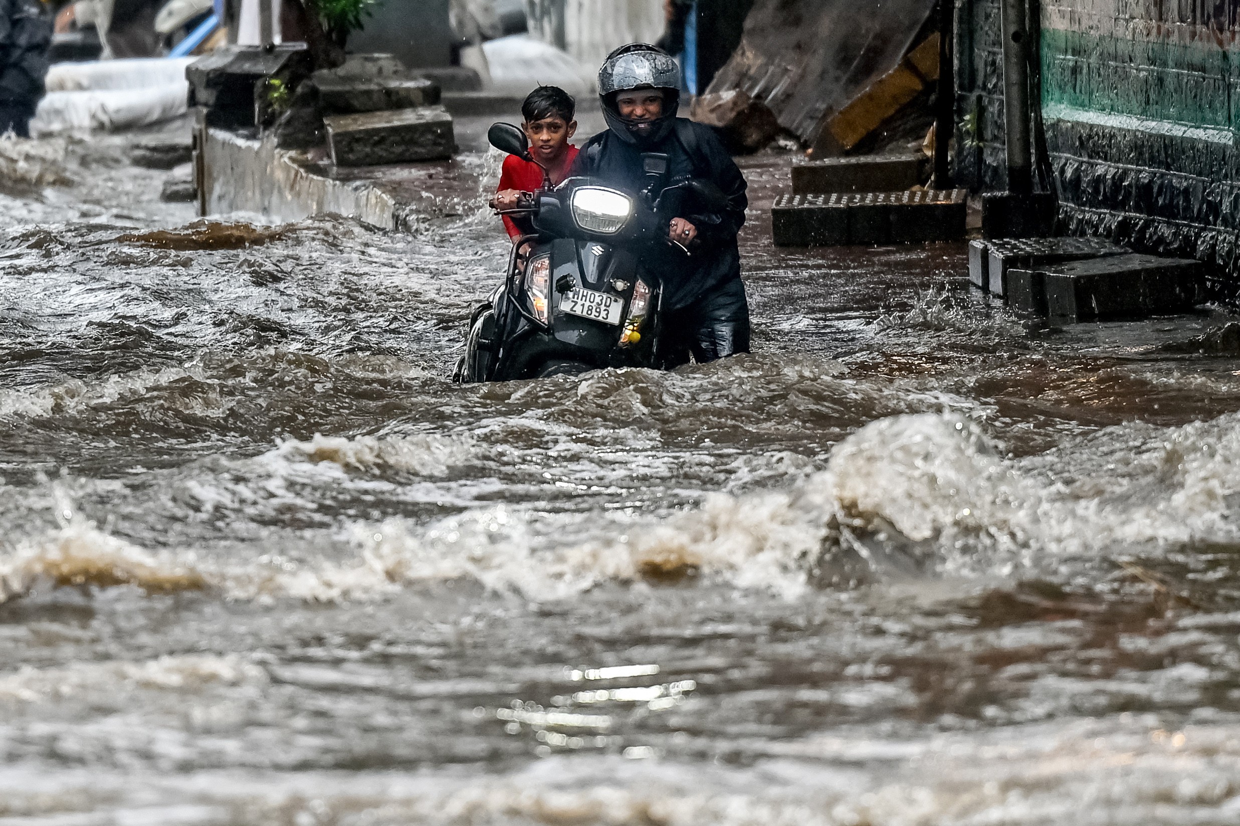 A person pushes the scooter toward the flood.