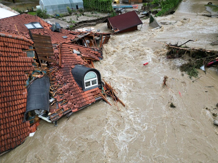 The roof of a destroyed house rests in rushing floodwater.