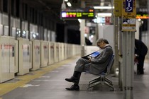 A man in business attire sleeps on a subway bench