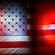 A photo of an American flag with red, white, and blue neon lights shining through it