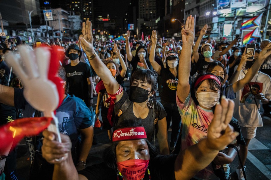 Protesters hold up a three-fingered salute in a street in Bangkok.