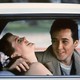 John Cusack and Ione Skye laugh together in a car.