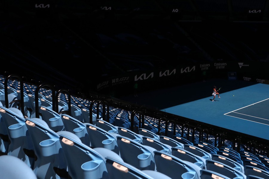 A player returns a ball in front of many empty seats.