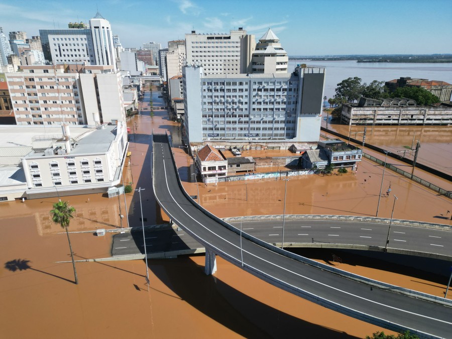 Flooding covers roads along a shoreline and beneath highway overpasses.