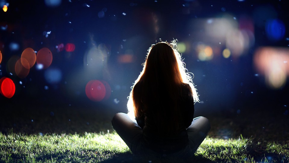 A girl sits in front of a blurry night sky