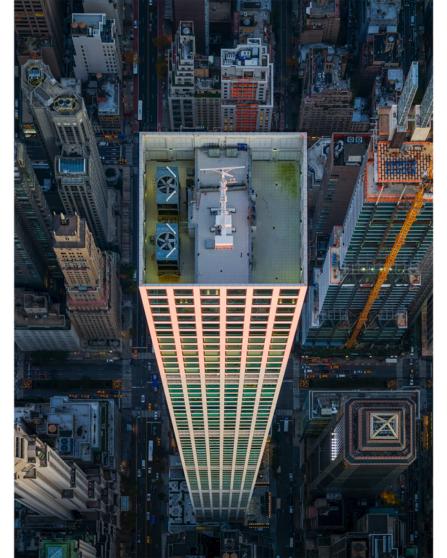 vertical, aerial-view photo of supertall skyscraper showing roof and other buildings/streets far below it
