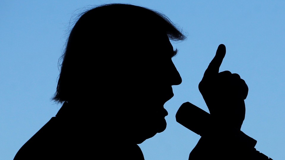 A silhouette of Donald Trump talking into a microphone with his finger pointing to the sky.