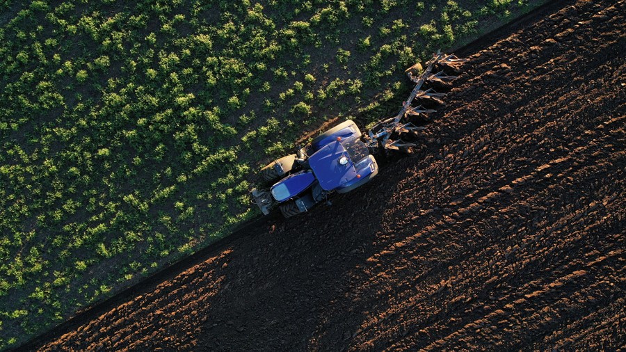 An aerial view of a tractor being used to plow a field.