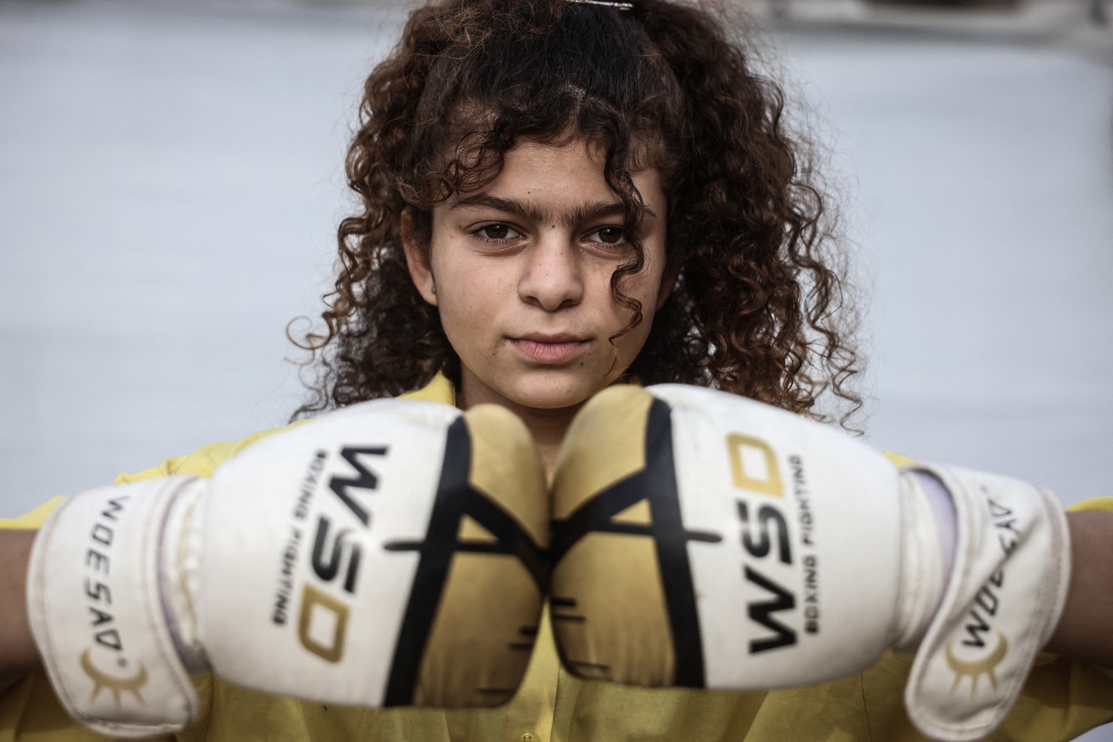A Palestinian girl poses with her boxing gloves during a training session.