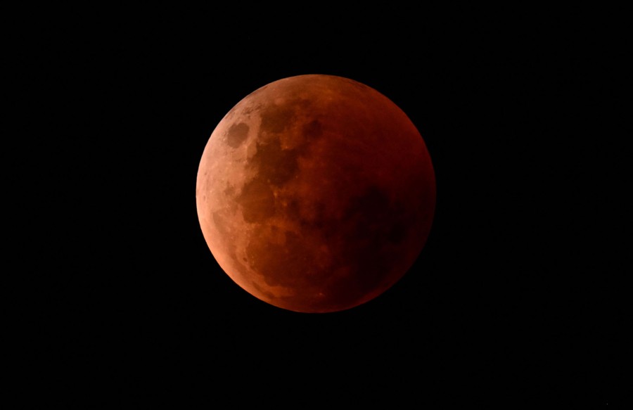 The moon in the night sky, dim and red-colored