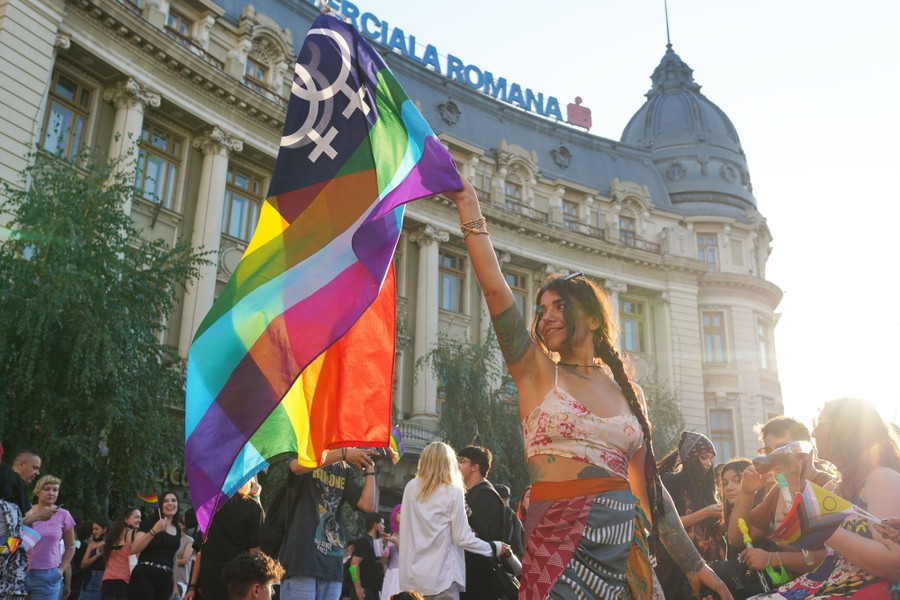 A group of people march together as one carries a rainbow flag.
