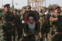 Members of the Abbas combat squad, a Shiite militia group, carry a picture of Grand Ayatollah Ali al-Sistani.