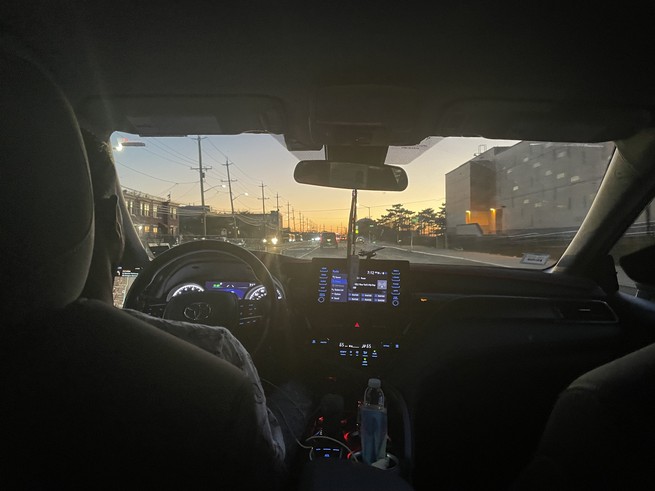 View out the front window of a car at sunset.