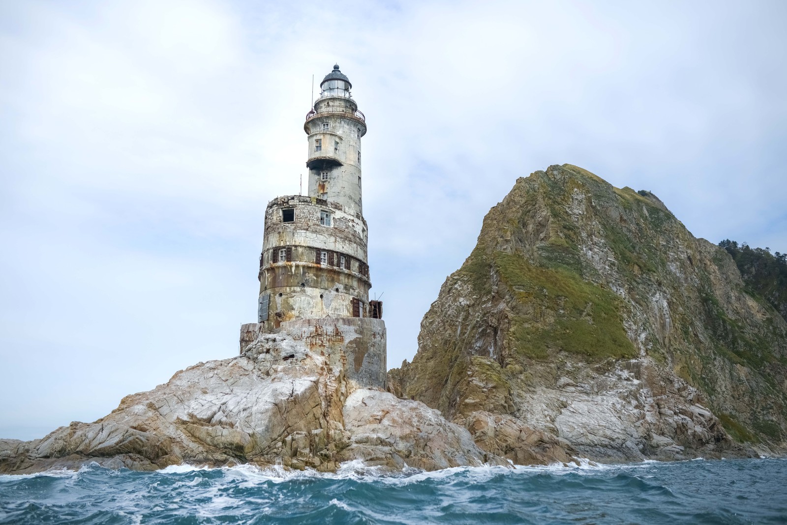 A crumbling, abandoned lighthouse, built onto a rocky cliff