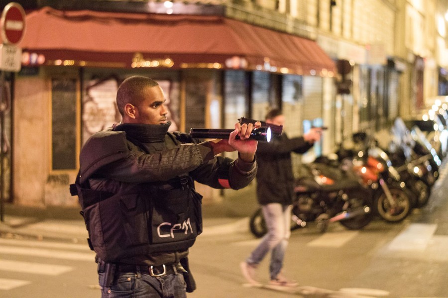 A police offers aims a flashlight and his gun at a target out of frame.