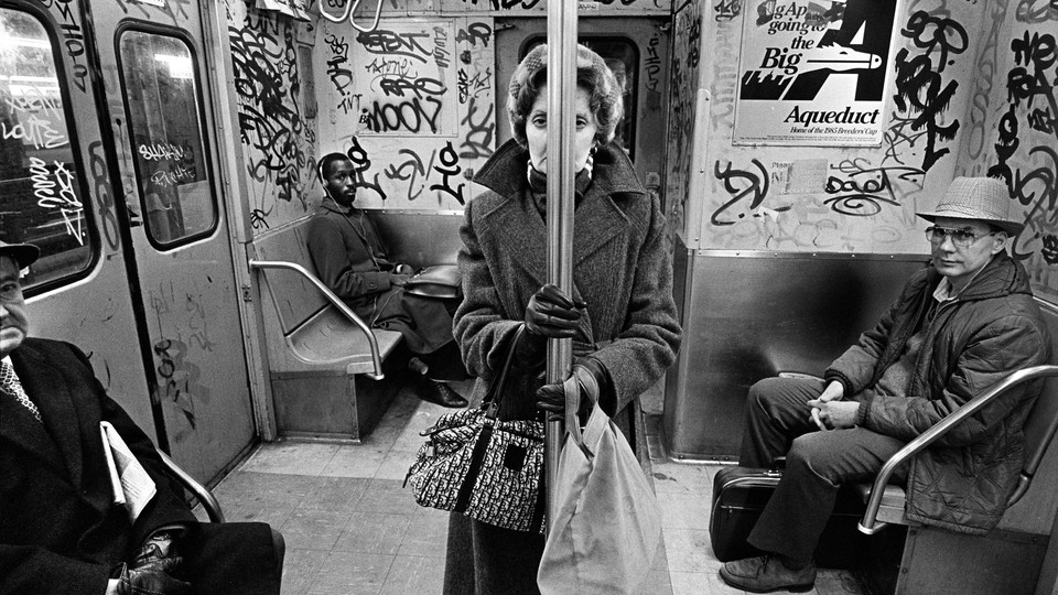 A woman hides behind a pole in a New York subway car.