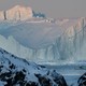 A fishing boat passes large icebergs.