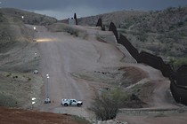 Customs and Border Patrol agent patrols along the international border after sunset in Nogales, Ariz.