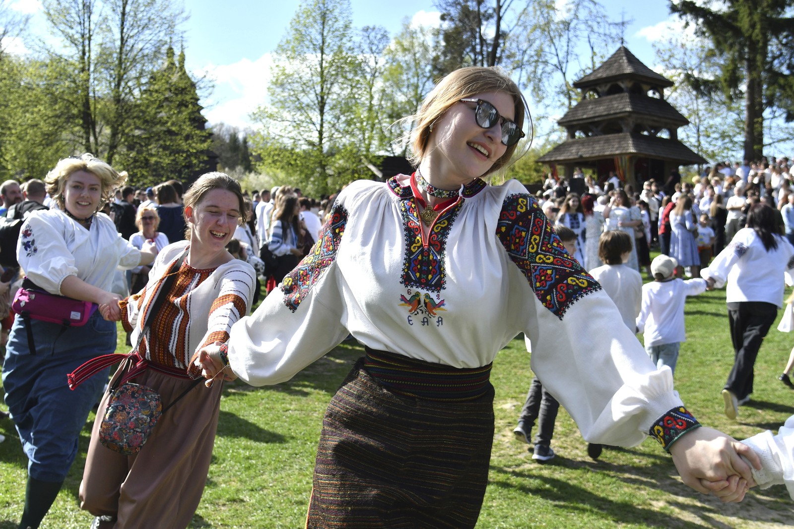 People dance outside in traditional Ukrainian clothing.