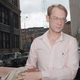 A photograph of Goetz on the way to his trial, wearing a pink button down shirt and glasses.