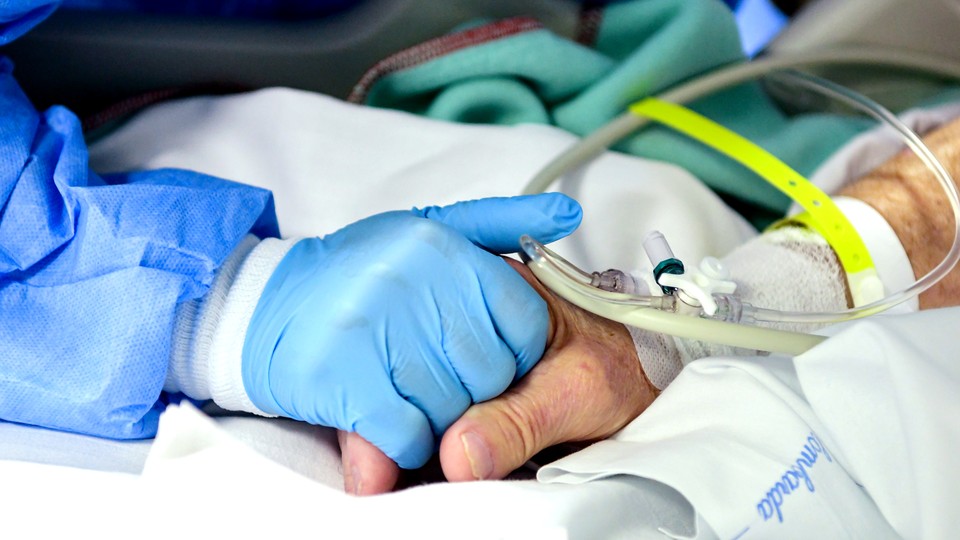 A health-care worker holding a patient's hand