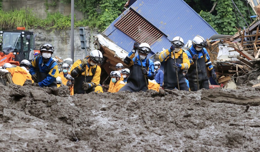 Police officers dig through thick mud and debris.