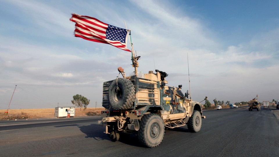A convoy of U.S. military vehicles travels down a road in Iraq.