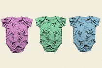 A row of baby onesies: one pink, one green, and one blue, each covered in a similar bamboo print.