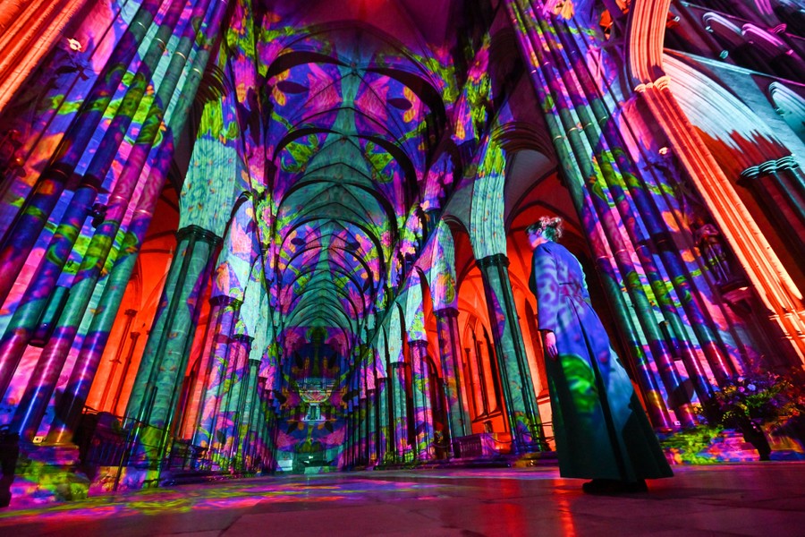 Bright and colorful lights are projected across the interior of a cathedral.