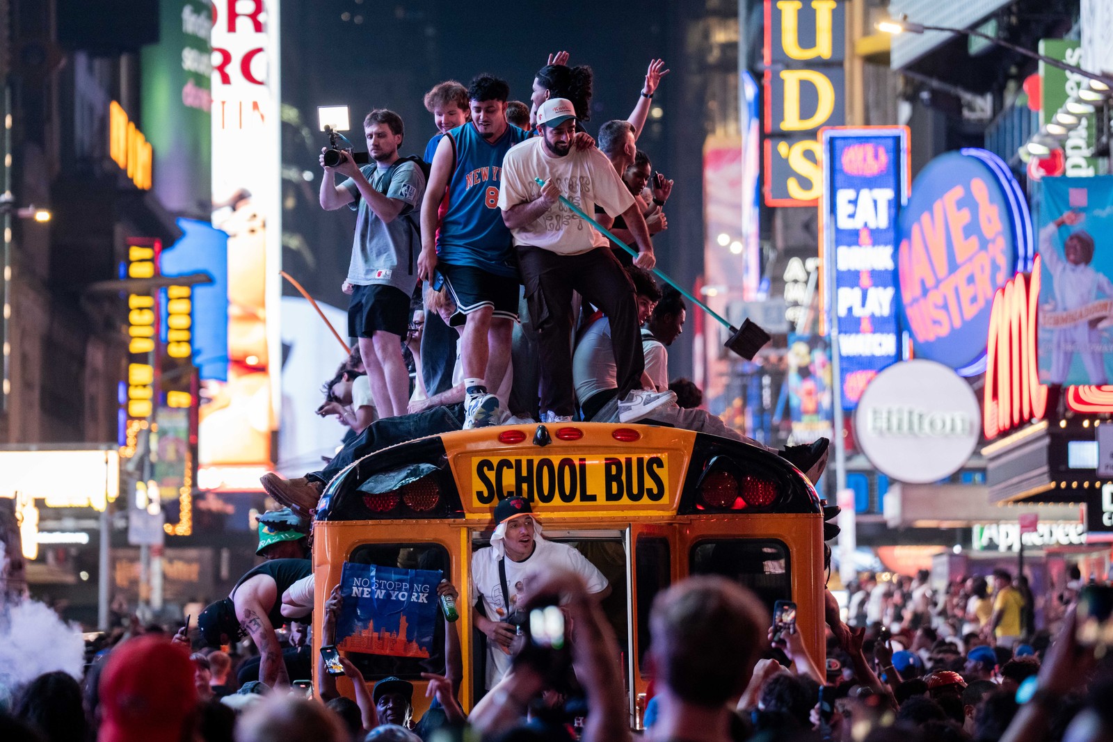 Knicks fans climb on school buses as they celebrate in Times Square.