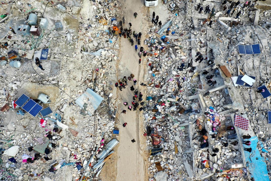 An aerial view of residents searching for people amid the rubble of collapsed buildings