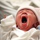 A baby yawns in a hospital.
