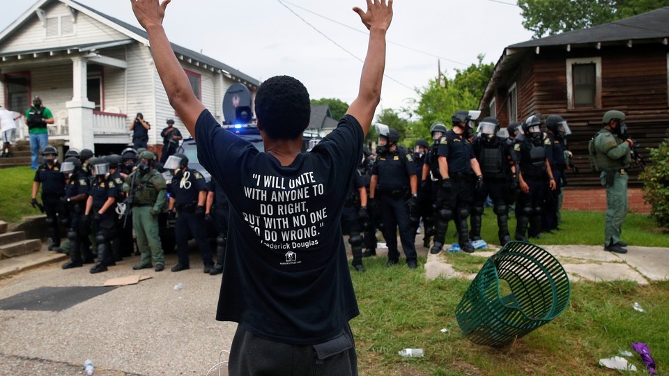 A demonstrator raises his hands in front of police in riot gear during protests in Baton Rouge, Louisiana, U.S., July 10, 2016. 