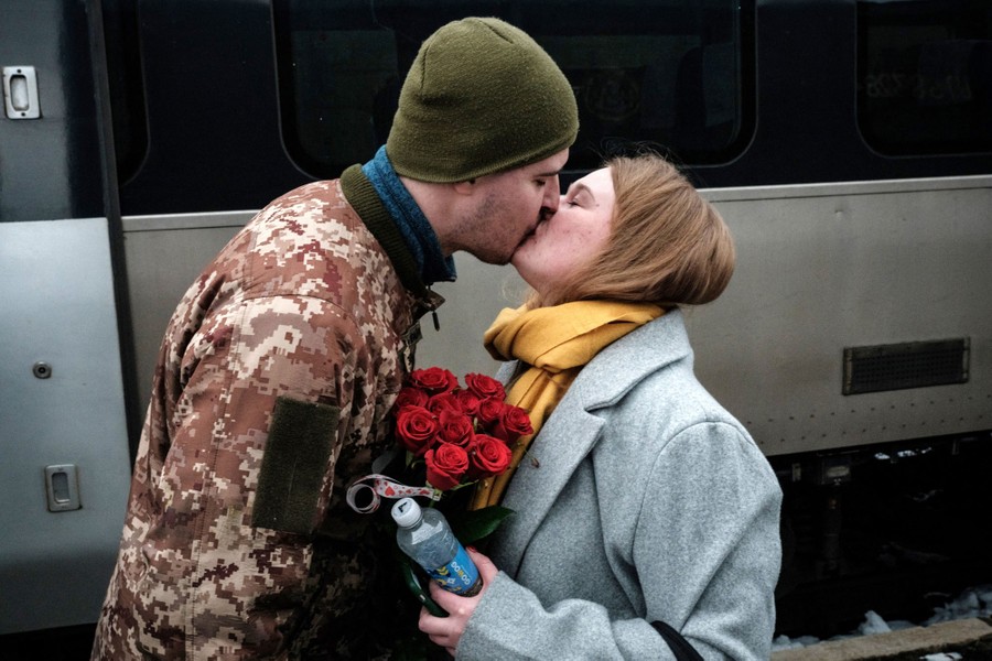 A soldier kisses his wife in a train station.